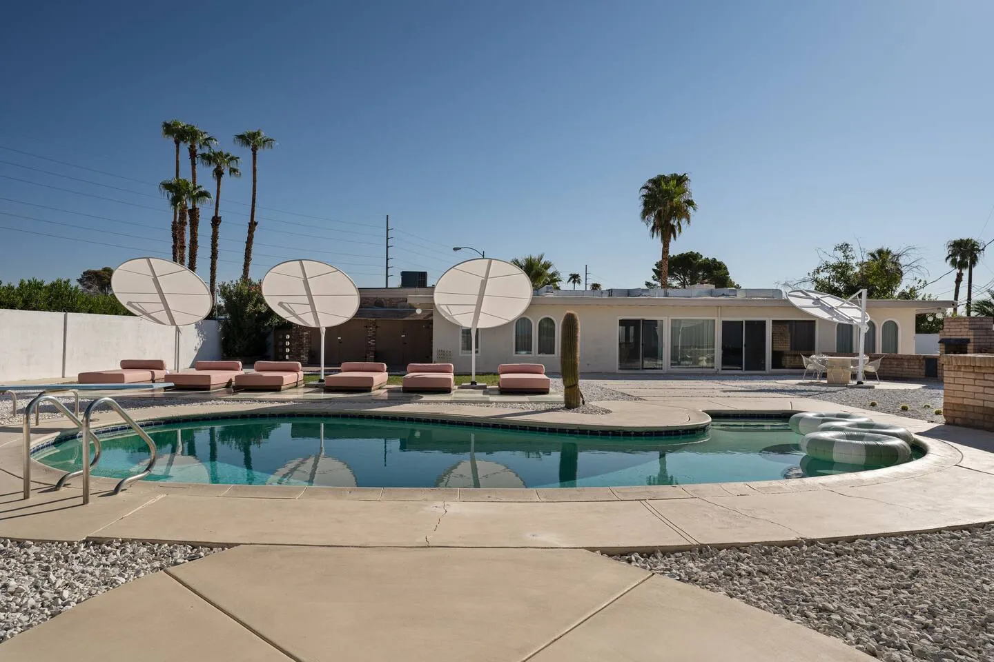 Arapaho property backyard swimming pool with lounge chairs and umbrellas