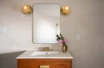 Arapaho property bathroom vanity with wooden cabinet, mirror, and flowers