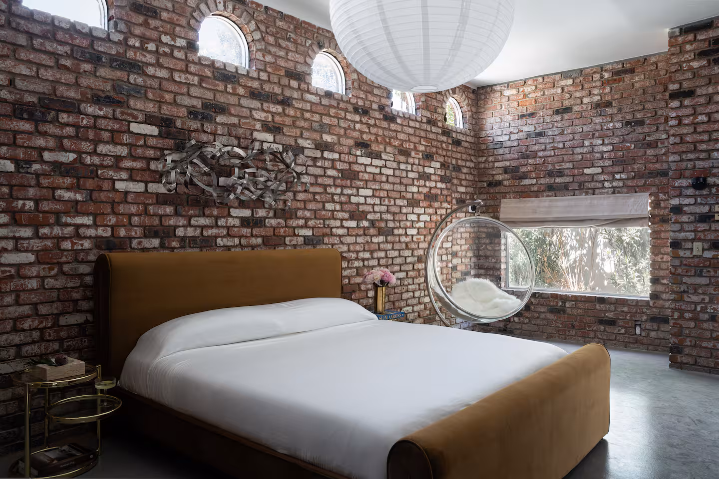 Arapaho property bedroom with brick walls, modern bed, and hanging chair