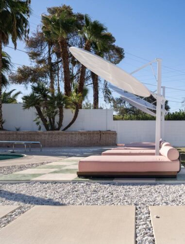 Arapaho property poolside area with sun loungers and palm trees